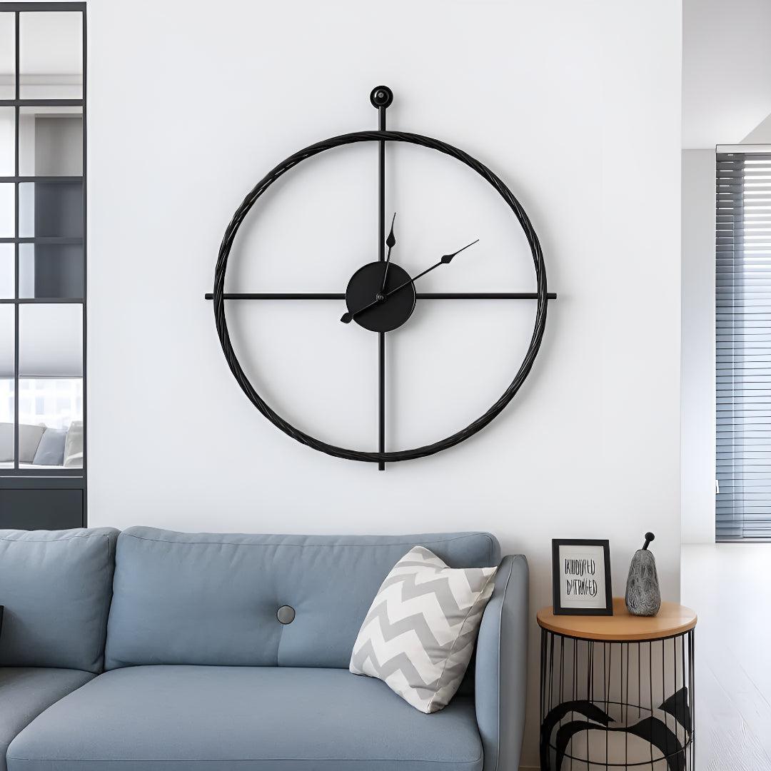 Large silent wall clock with minimalist open-frame design above a light blue sofa in a modern living room.